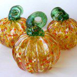 Three glass pumpkins are sitting on a table.