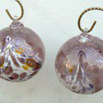 Two glass ornaments with a gold string hanging from the bottom.