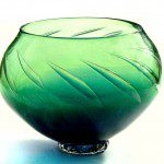 A green glass bowl sitting on top of a table.