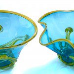 Two blue glass bowls with yellow trim on a table.
