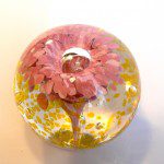 A pink flower in a glass ball with a ring inside.