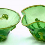 Two green glass bowls with a leaf design on them.