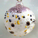 A glass ornament with black, yellow and white dots.