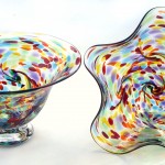 A bowl and plate with colorful glass on them.
