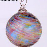 A rainbow colored glass ornament hanging from a wire.