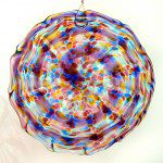 A colorful glass dish hanging on the wall.