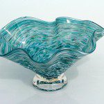 A glass bowl with blue and green swirls on top of it.