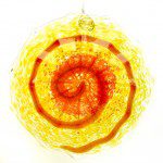 A yellow and orange glass ornament with a spiral design.