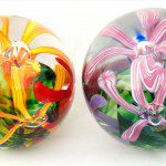 Two glass balls with flowers on them sitting next to each other.