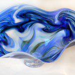 A glass bowl with blue and green swirls on it.