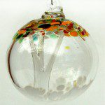 A glass ornament with trees and dots on it.