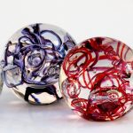 Two glass sculptures of a red and blue ball.