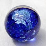 A blue glass ball with silver foil on it.