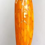 A tall orange vase with gold specks on it.