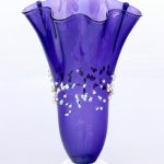 A purple vase with white flowers on top of it.