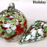 A glass ornament with red, white and green design.