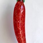 A red pepper with green leaves on it.