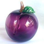 A purple apple with green leaf on it.