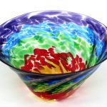 A bowl with colorful swirls of glass on it.