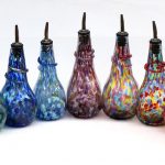 A group of colorful glass bottles with tops.