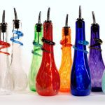 A group of colorful glass bottles with metal tops.